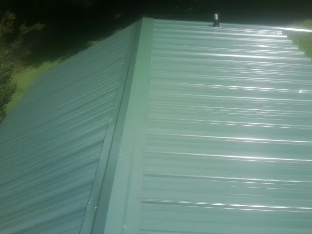 New green metal panels meeting at the ridge of a roof — Flat Roof Repair work by our crew in Pittsboro