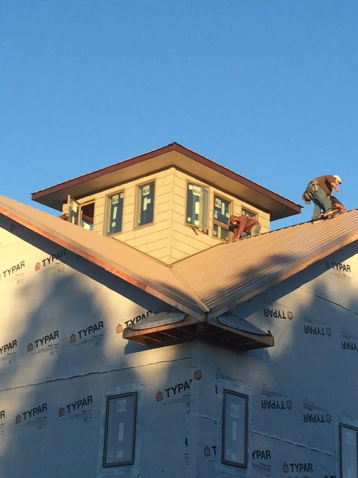Roofers working around a rooftop cupola on a new metal roof at sunset — Roof Waterproofing in Pittsboro by Roofing Brothers